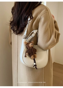 Detail of white lychee pattern moon bag with a cute teddy bear charm and adjustable strap