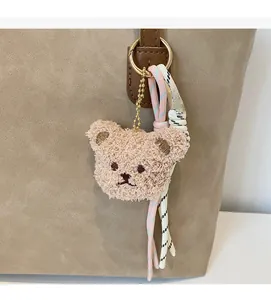 Detailed close-up of a plush bear charm with woven straps on a khaki tote bag