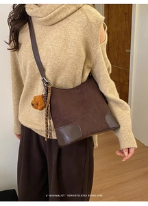 Détail du sac seau en daim marron foncé avec finitions cuir et charm ours en peluche doux
