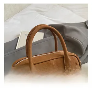 Detail shot of brown lychee grain leather handbag with dual handles and metal buckles