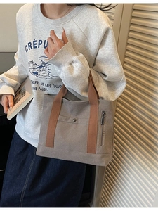 Minimalist grey canvas tote bag with brown handles and side pocket for daily commute