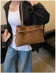 Brown vintage leather tote bag styled with a black blazer and casual jeans