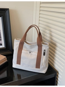 Large beige canvas tote bag with brown straps and functional zipper pocket