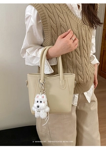 Détail d'un sac seau en cuir beige grainé avec un charmant pendentif chien en peluche