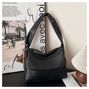 Detail of black oil wax leather tote bag featuring star pendant and wide shoulder strap