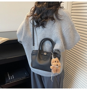 Détail du sac seau noir en cuir grainé avec boucle argentée et breloque ours en peluche