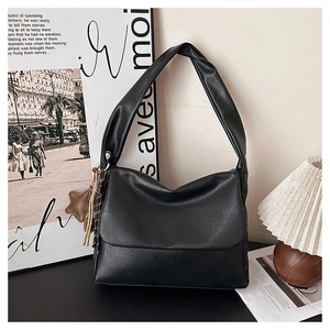 Detail of minimalist black faux leather tote with brown star charm and woven strap detail