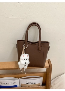 Close-up of brown litchi pattern leather tote bag with cute plush puppy charm