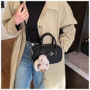 Detail of matte black bowling bag with silver buckle and plush rabbit charm