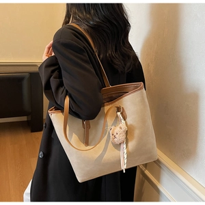 Detail of khakhi suede tote bag with brown leather straps and cute plush bear charm