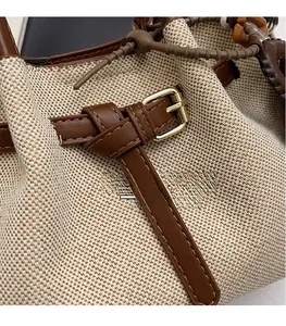 Close-up of beige woven canvas and brown leather stitching with gold buckle detail