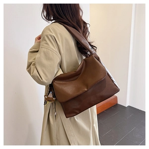 Detail view of large brown oil wax leather tote bag with cute bear charm on shoulder