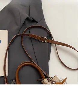 Close-up of adjustable brown leather shoulder strap with gold metal buckle detail