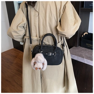 Close-up of retro black bowling bag with silver buckle and plush bunny charm on model