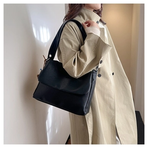 Close-up of minimalist black oil wax leather tote bag worn by model in soft natural light