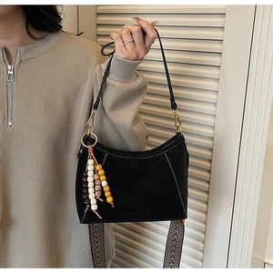 Detalle de bolso hobo de ante negro con cuentas de madera y correa estampada