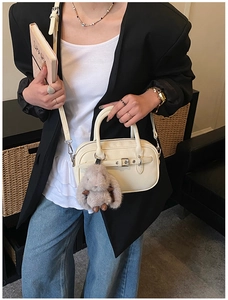 Detail view of beige square bag with lychee texture and cute plush rabbit charm