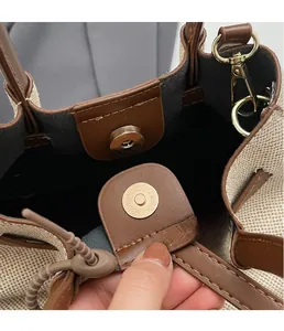 Close-up of golden magnetic buckle closure on canvas and brown leather handbag
