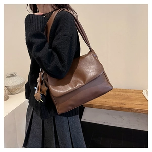 Detail of dark brown leather tote bag with star charm worn with casual outfit