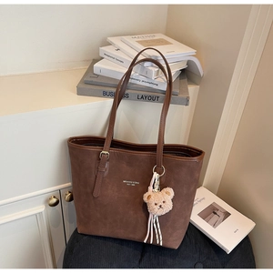 Detail of dark brown faux suede tote bag featuring MIKAXIQI logo and cute bear charm