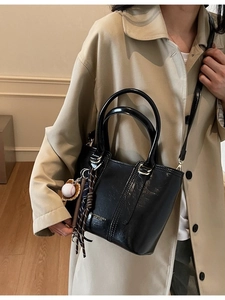 Retro black glossy bucket bag with round handles and baseball charm accessory