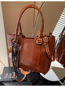 Retro brown bucket bag with shiny leather texture and woven strap detail for women