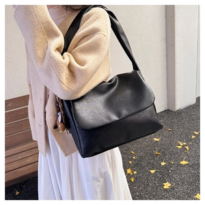 Detail view of black oil wax leather tote bag with cute bear charm worn on street