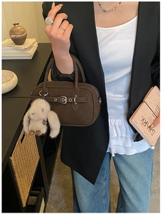 Detail of dark brown matte leather handbag with silver buckles and plush rabbit charm