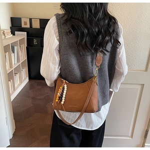 Detalle del bolso de cuero marrón con borlas de cuentas y correa de estilo étnico