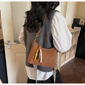 Detalle de bolso hobo vintage marrón con borla de cuentas de madera y correa tejida