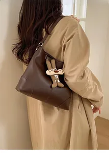 Detail of soft leather tote bag in dark brown with a cute cartoon charm on strap