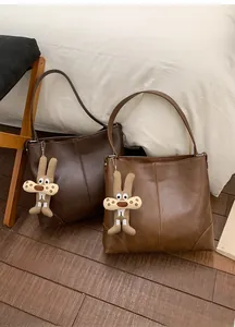 Detail view of large soft leather tote bags in dark brown and caramel with plush charms