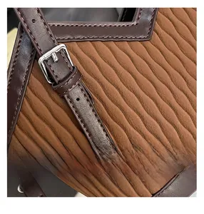 Détail d'un sac à main en cuir plissé marron avec boucle argentée et surpiqûres