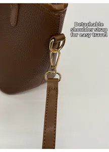 Detail of detachable brown leather shoulder strap with gold metal swivel hook on bucket bag