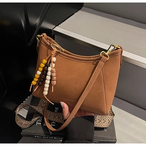 Detalle del bolso hobo de cuero marrón con cuentas de colores y correa elegante