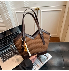 Nahaufnahme braune Steppmuster Eimertasche mit Ledergriffen und bunter Holzperlenkette