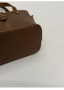 Macro detail of dark brown lychee leather bucket bag with wide reinforced bottom base