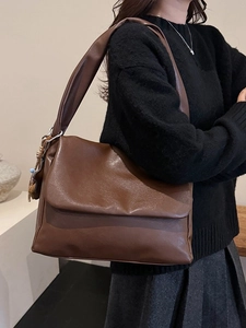 Minimalist caramel brown oil wax leather tote bag with a woven charm and wide strap
