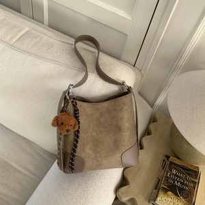 Close-up of brown suede hobo bag with teddy charm and textured leather corner details