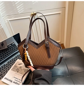 Detail der Retro-Beuteltasche mit vertikalen Falten und dekorativem Perlenanhänger