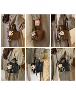 Detail view of leather bucket bags with plush bear charms and pearl chain decorations