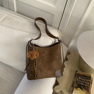 Detailed view of a dark brown suede bucket bag with a cute plush dog pendant charm