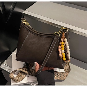Detalle del bolso de hombro vintage marrón oscuro con costuras y borla de cuentas