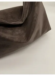 Close-up of dark brown soft leather texture with natural litchi grain on large hobo bag