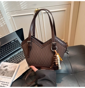 Detail der braunen Falten-Beuteltasche mit V-Schnitt und ethnischem Perlenanhänger