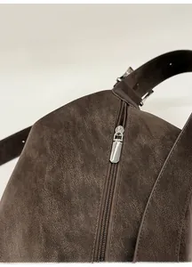 Detail of silver metal zipper and vintage matte leather texture on dark brown tote bag