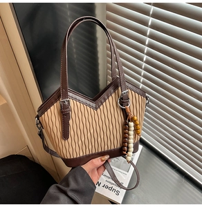 Detail der Bohème-Plissee-Beuteltasche mit braunem Lederbesatz und dekorativen Holzperlen