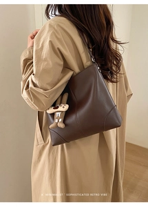 Detail of retro dark brown leather tote with stitching and cute plush bunny charm