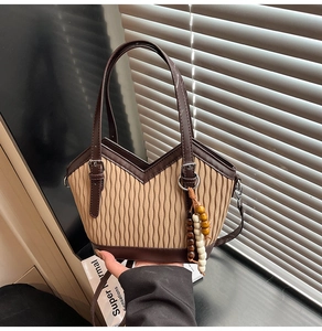 Nahaufnahme der beige plissierten Beuteltasche mit braunem Lederbesatz und Holzperlen