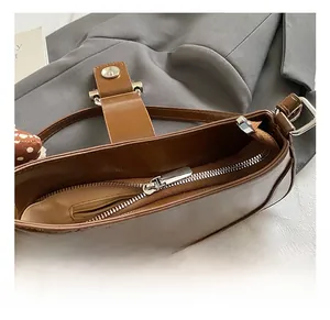 Close-up of premium brown leather underarm bag featuring silver zipper and hardware details